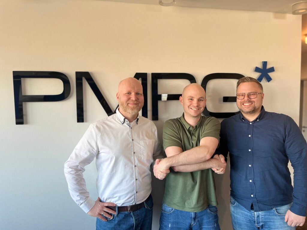 PMPG in Bonn: Florian Kutschke, Björn und Fabian Geller schütteln sich vor dem PMPG-Logo die Hand